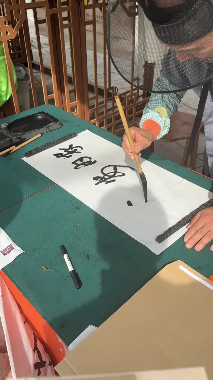 Calligrapher writing a household motto with a brush at the park festival